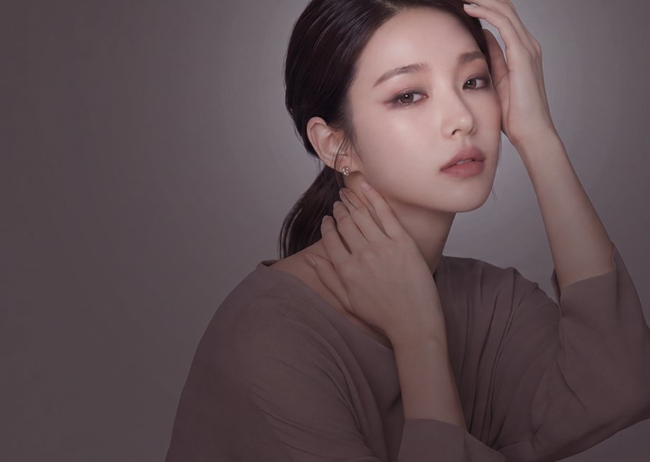 광고 모델 — 한 손은 목에, 한 손은 머리에 댄 포니테일 여성(회갈색 배경)
