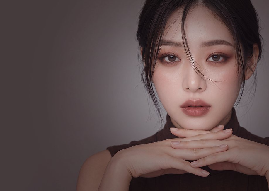 광고 모델 — 깍지 낀 두 손 위에 턱을 괸 여성(어두운 배경)
